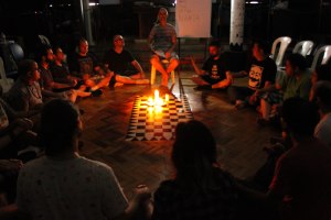 People sitting in a circle around lit candles in a dark room