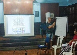 A man teaching a seminar near a projector screen and flipchart
