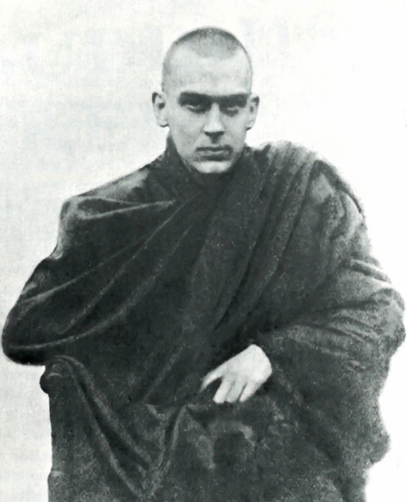 Black-and-white photograph of a shaved-head man in a dark traditional monk robe