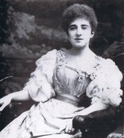 Vintage black-and-white portrait of a seated woman in an ornate Victorian-style gown, facing camera