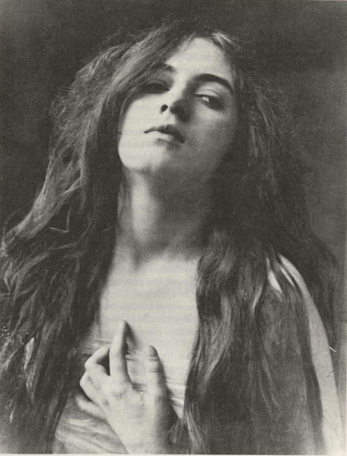 Vintage black-and-white portrait of a woman with long dark hair, intense gaze, hand near heart