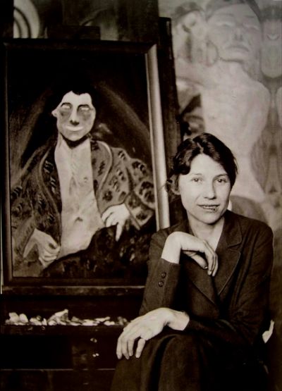 Vintage photograph of a woman in an art studio next to a portrait painting on an easel