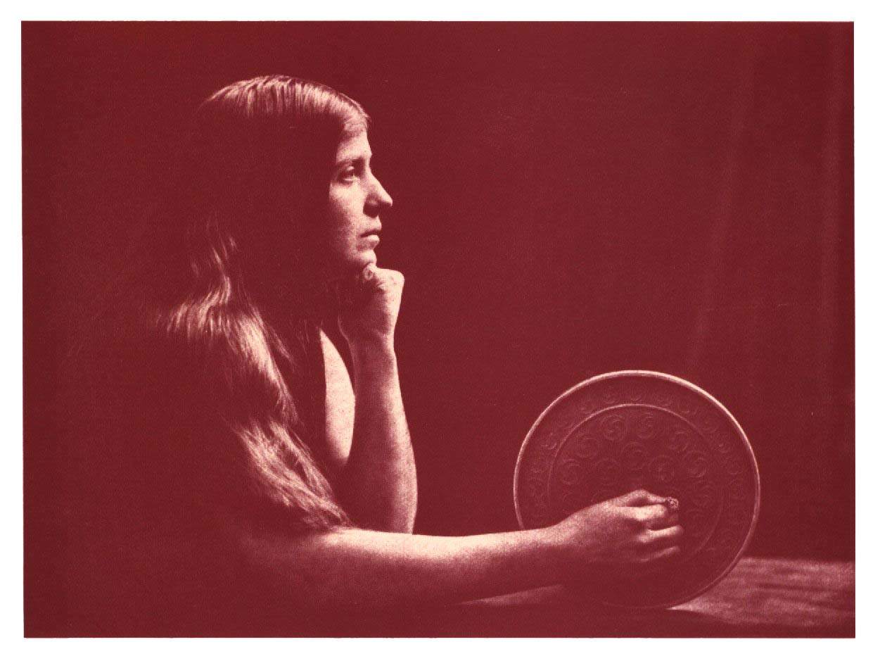 Sepia-toned vintage portrait of a woman in profile holding a circular decorative disk