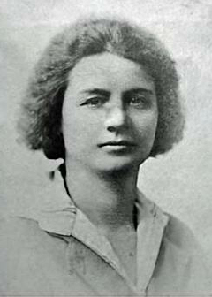 Black-white studio portrait of a woman with short, curly hair wearing a simple collared shirt