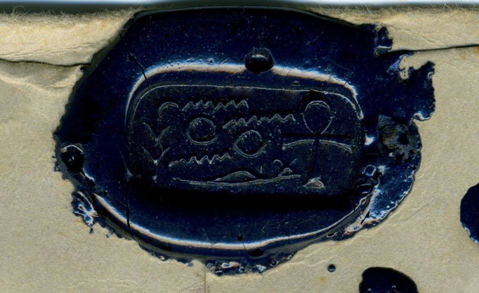 Close-up of dark blue oval wax seal with Egyptian-style cartouche, hieroglyphs, and ankh symbol on right
