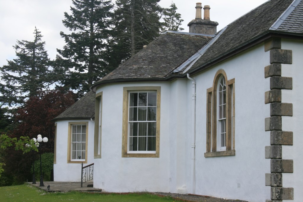 Side view of Boleskine House with curved bay windows, stone arches, slate roof