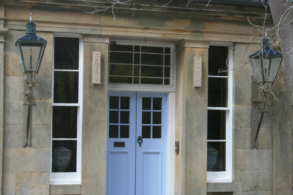 Close-up of Boleskine House’s light blue double doors, flanked by tall windows and vintage lanterns
