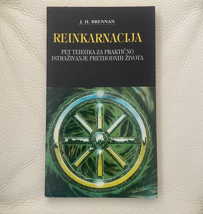 Book cover of "Reinkarnacija" by J. H. Brennan, featuring a glowing green and yellow Dharma wheel illustration on a black background